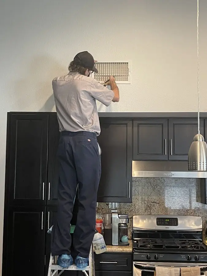 Technician inspecting an air vent during HVAC service in Compton